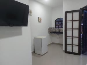 a room with a refrigerator and a television on a wall at Apart Hotel Guaiuba in Guarujá