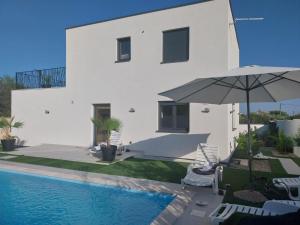 a white house with a swimming pool and an umbrella at Villa Providenca in Poličnik