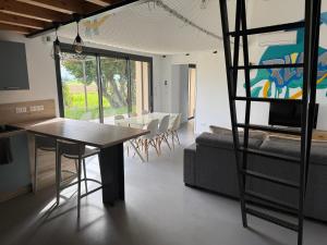 a dining room and living room with a table and a ladder at Gîte PLACE FOR YOU in Beaumont-lès-Valence