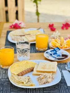 a table topped with plates of food and orange juice at Aquatic Mathiveri in Mathiveri