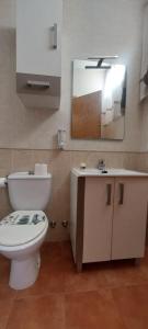 ein Badezimmer mit Toilette, Waschbecken und Spiegel in der Unterkunft Preciosa casa con piscina y golf in El Portil + 12 Fotos