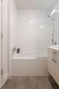 a white bathroom with a tub and a sink at Cute 1BDR Apt in Ste-Catherine - MTL Live Spot in Montréal