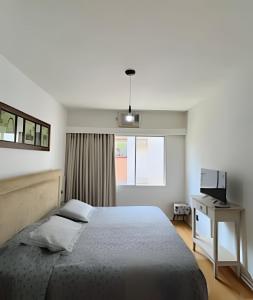 a bedroom with a bed and a desk and a television at Flat espaçoso, super confortável e moderno in Ribeirão Preto +28 photos