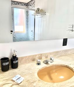 a bathroom counter with a sink and a mirror at Flat espaçoso, super confortável e moderno in Ribeirão Preto