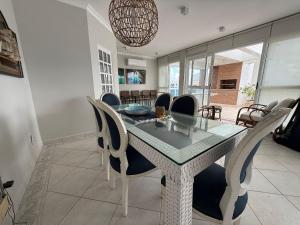 ein Esszimmer mit Glastisch und Stühlen in der Unterkunft Cobertura com Piscina Privativa e Vista Mar in Riviera de São Lourenço