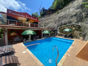 a pool at a hotel with chairs and umbrellas at Pousada Eco Beach in Ubatuba