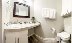 a white bathroom with a sink and a mirror at SFA Retreat, Spacious Downtown Apartment in Nacogdoches +4 photos