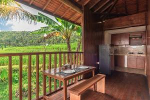 a wooden balcony with a table and a refrigerator at Villa Sande in Munduk
