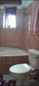 a bathroom with a toilet and a tub and a window at Coincom Apartments in Kampala