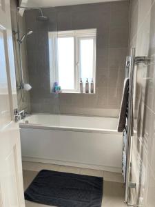 a bathroom with a white bath tub and a window at Spacious 3 bed with driveway in Manchester +17 photos