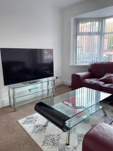 a living room with a tv and a glass coffee table at Spacious 3 bed with driveway in Manchester