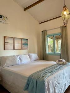 a bedroom with a large white bed with a window at Pousada Safyra in Caraíva