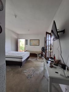 Casa em Buzios MATO - PRAIA في بوزيوس: غرفة نوم بها سرير ومكتب وتلفزيون +8 صور
