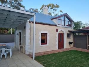 a small house with a patio and a table at 1860 Heritage Beachside Studio in Somerton Park