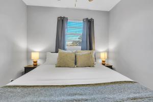 une chambre avec un grand lit blanc avec deux lampes dans l'établissement SMV Cute Jacksonville Bungalow Central, à Jacksonville