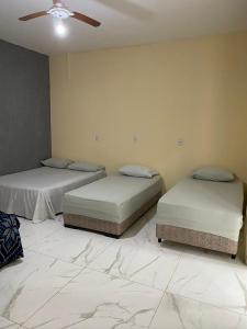 2 Betten in einem Zimmer mit Deckenventilator in der Unterkunft Casa Colorado Thermas Laranjais Olimpia in Olímpia