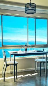 a table with wine glasses and two chairs in front of a window at Departamento a Orilla del Lago in San Carlos de Bariloche