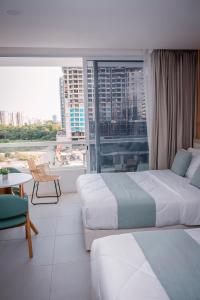 a hotel room with two beds and a large window at Porto Horizonte Suite 735 in Santa Marta +37 photos