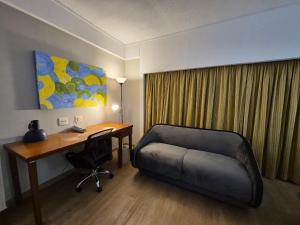 a room with a desk and a couch next to a desk and a deskablish at Flat King Vila Mariana Ibirapuera (Apto 401) in São Paulo