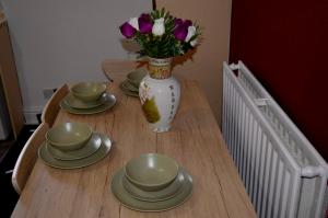 a wooden table with plates and a vase with flowers at Stylish 1 bedroom Flat central Skegness F9 in Skegness +4 photos