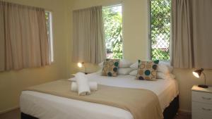 two beds in a bedroom with two windows at Del Haven Holiday House in Arcadia