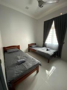 a bedroom with two twin beds and a window at Tok Jiring Boutique Homestay in Kuala Terengganu