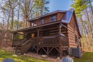 a cabin in the woods with a large deck at Hidden Hideaway in Cosby