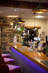 a bar in a restaurant with purple lighting at Cross Foxes - Bar Grill Rooms in Dolgellau