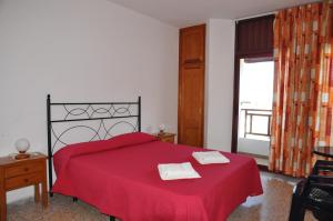 a bedroom with a red bed with two towels on it at Apartamentos Restinga in La Restinga