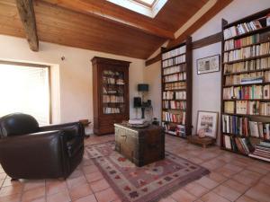 a living room with a leather chair and book shelves at Gîte familial spacieux avec piscine naturelle, proche Nantes - FR-1-306-1218 in La Limouzinière