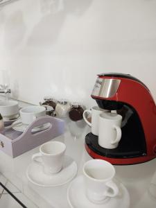 una macchinetta del caffè con tazze e piattini su un bancone di Casa Florescer a Salvador