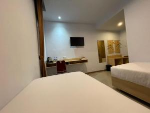 a room with two beds and a desk and a chair at Wisma SIDAPORE JD in Lamobuang +18 photos