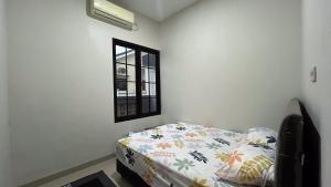 un dormitorio con una cama y una ventana en Omah Gedongan Homestay, en Sawahan