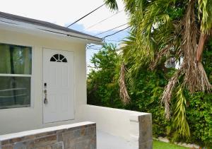 a white door on a white house with trees at Spacious Studio 10 mins to Mia&Downtown in Miami