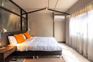 a bedroom with a bed with orange pillows and a window at Thip Residence at Surawong in Bang Rak