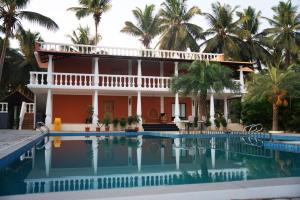 a house with a swimming pool and palm trees at Metro Club Resort in Kāmānayakkanpālaiyam +33 photos