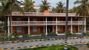 a building with a balcony and palm trees at Metro Club Resort in Kāmānayakkanpālaiyam
