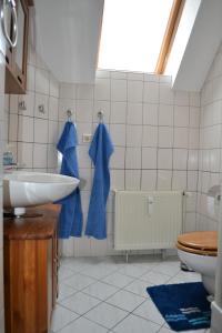 ein Badezimmer mit einem Waschbecken und einem WC mit blauen Handtüchern in der Unterkunft Ferienwohnung Schleussig in Leipzig