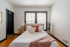 una camera da letto con un grande letto bianco con cuscini arancioni di Stay Portland - Spacious Restored Craftsmen - Craft Beer & Coffee a Portland