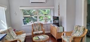ein Wohnzimmer mit Stühlen und einem Tisch und einem Fenster in der Unterkunft Coconut Cottage Christmas Island in Flying Fish Cove