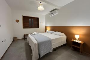 um quarto com uma cama branca e uma televisão em Casa Brisa do Vale - Lençóis - BA em Lençóis