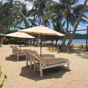 un gruppo di sedie e ombrelloni in spiaggia di The Sanctuary a El Nido