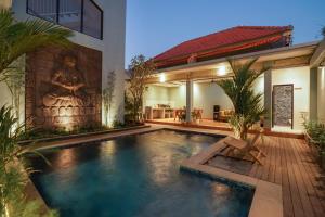 a swimming pool in front of a house at Navee Studio Apartments Canggu in Munggu