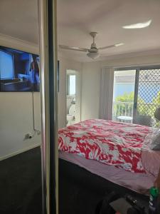 a bedroom with a red bed and a window at Kallangur 3 Bedroom Townhouse in Kallangur