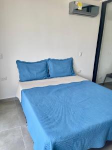 a bed with blue pillows in a room at Tamarielys 1BR Vista a la montaña in Rodadero