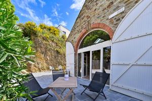 eine Terrasse mit Stühlen, einem Tisch und einem Torbogen in der Unterkunft La Cormorane - 100m plage - Parking in La Plaine-sur-Mer
