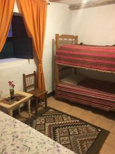 a room with two beds and a chair and a table at Nilo Trek House in Chiquián