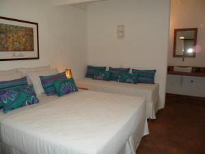 two beds in a room with blue and green pillows at Jardim de Trancoso Pousada in Trancoso