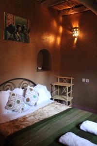 1 dormitorio con 1 cama con sábanas y almohadas blancas en Kasbah Maison D’hôte Lalla Zahra en Aït Baha