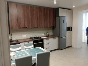 a kitchen with a table and a stainless steel refrigerator at Люкс залізничний вокзал in Luts'k +1 photo